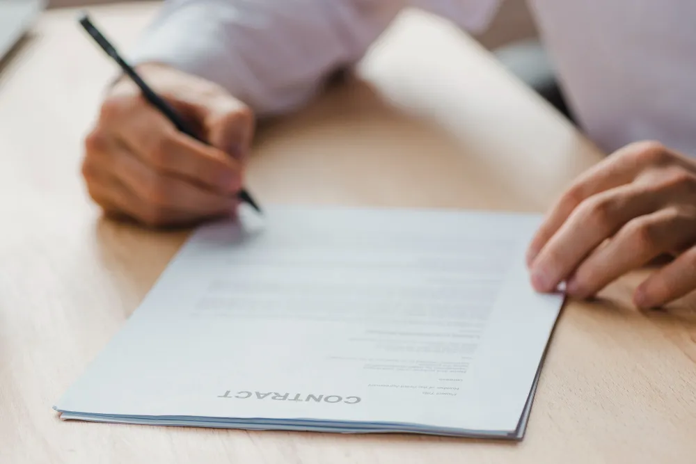 Mão escrevendo em contrato, detalhe para aposentadoria da pessoa com deficiência.