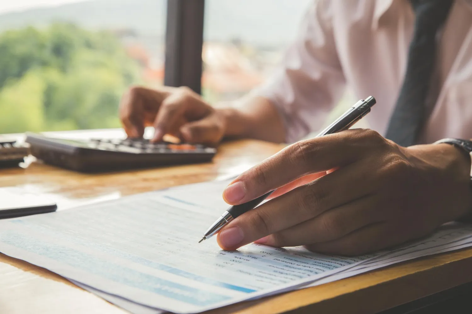 Pessoa calculando tempo de contribuição mínimo para aposentadoria em documentos.